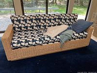 Front view of wicker sofa with patterned cushions, throws and pillow