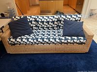 Front view of entire wicker couch with printed seat and back cushions and two throw pillows