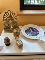 Photo of lot showing brass bookend, three decorative eggs of varying types and sizes, and Washington DC souvenir plate.