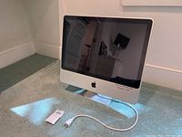 Front angle showing the iMac screen, Apple logo, power cable, and overall design.
