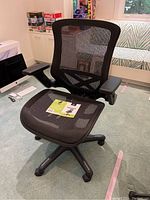 Front angled view of the black mesh office chair with manufacturer tag on seat.