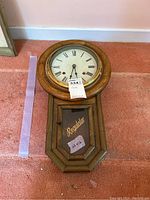 Full view of the regulator clock showing wooden case, clock face with Roman numerals, and glass door with 'Regulator' lettering.