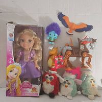 Boxed Disney Princess Toddler Rapunzel doll, Furbies, Pokémon Charmander figure, small plush and plastic toys. Various colors and types.