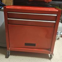 Front view of red rolling tool chest with three drawers and cabinet, showing its overall design.
