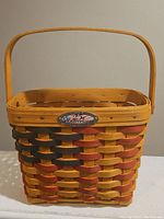 Front view of the rectangular woven basket with handle and anniversary badge.