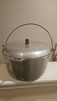 Side view of vintage Wagner 736 kettle pot with lid and wire handle, showing overall condition and design.