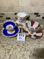 Front view of 3 vintage cups and saucers on countertop showing decorative patterns