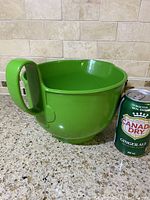 Image of green Dansk Gourmet Designs mixing bowl next to a 355ml Canada Dry ginger ale can for scale, showing the curved handle and pouring spout.