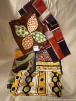 Mixed lot of vintage scarves with various colorful geometric and abstract patterns folded together.