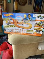 Front view of unopened Hot Wheels slot car track set box featuring kids playing and track layout with loop.