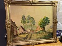 Full view of the framed oil painting showing multiple houses and trees in a rural setting.