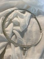 Full view of the silver tone vintage choker necklace laid on a white fabric background, showing overall design and clasp.