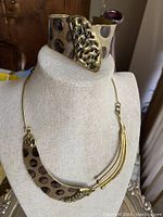 Vintage Brutalist cuff bracelet on display with gold-tone textured and irregular pattern with black or dark patina accents