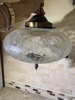 Photo showing the vintage ceiling pendant light hanging, displaying the crackled glass shade and ornate brass fitting at the top with finial at the bottom.