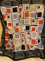 Top view of the full scarf showing geometric pattern in black, white, red, and grey squares and rectangles.