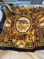Full view of vintage silk scarf featuring a large central tiger and patterned animal print background with black and gold ornate border.
