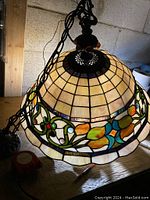 Side view of vintage stained glass hanging lamp showing cream and beige glass panels with chain and brass fixture on top.