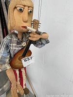 Close-up of the puppet showing the hand holding the guitar and the cigarette.