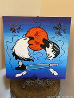 Full view of the Woodlands style painting featuring eagle, wolf, red sun and feathers on blue background.