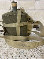 WW2 British Army military canteen kettle covered in olive green canvas with beige carrying strap marked CN70356.