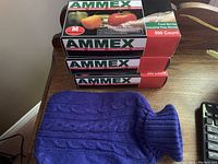 Three boxes of Ammex disposable polyethylene gloves stacked on a wooden surface