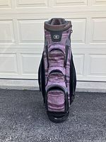 Front view of mauve and brown golf bag showing multiple zippered pockets and logo patch near top