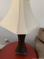 Photo of a large table lamp with heavy, hexagonal dark wood base and a large cream fabric shade.