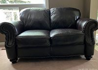 Front view of love seat showing two seat cushions, rolled arms and nailhead trim along base