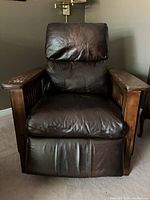 Front view of the leather recliner showing the seat cushion, back cushion, and wooden armrests.