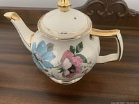 Side angle showing the floral design and gold accents on the teapot.