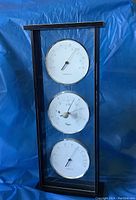 Full view of the Taylor triple desktop gauge in a black frame with three white dials against a blue background.