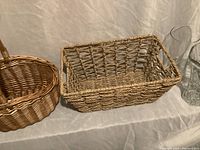 Rectangular basket and oval handle basket placed side by side on fabric background.