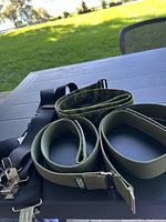 Three nylon webbing belts (olive green, camouflage, black) and one black suspenders with metal clips.