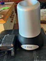 Compact Bravetti beverage chiller with black base and silver cylindrical upper part, power adapter plugged in beside it