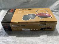 Closed box labeled Cuisiland showing image of red cast iron teapot and cups, indicating the set brand and package condition