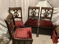 Four wooden chairs with brown finish and burgundy plush upholstered seats, arranged together showing front and side views.
