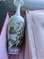 Vintage Chinese vase showing detailed oriental landscape design with pagoda, bridge, trees and water in blues and subtle colors. Vase approximately 10.25 inches tall, displayed in original box with fabric lining.