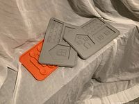 Three silicone molds: two gray rectangle molds with gingerbread house parts design and one orange mold for spoon shaped ice. Taken to show Pampered Chef baking item details.