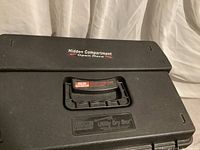 Top view of dry box showing black plastic surface with handle and label indicating hidden compartment under handle