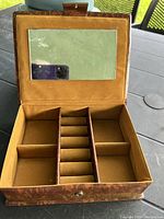 Brown padded embroidery jewelry box opened showing inner compartments for rings and jewelry, and a mirror attached to the lid.
