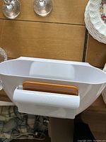 White plastic scrap catcher for kitchen use with an orange handle attachment.