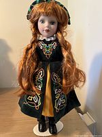 Porcelain Irish dancer doll 16-inch with red braided hair, black velvet dress with Celtic embroidery, yellow underskirt, black boots, on stand
