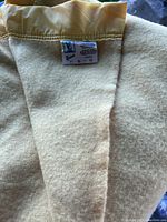 Close-up photo of the Kenwood wool blanket showing cream color and sewn label with care instructions.