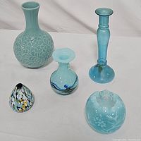 Photo of all five blue glass vases on white background showing different shapes and patterns