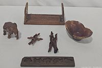 Overview of all wooden items: carved expandable bookshelf, elephant figurine, organic bowl, cookie/butter mold, and branch holders.