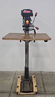 Front view of Craftsman 15" drill press showing wooden table, metal stand and drill head with control levers and power switch.