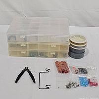 Wide view of the kit showing storage boxes, wire spools, small bags with findings, and pliers arranged on a white surface