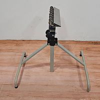 Front view of the metal stand with angled legs and caster wheels on top.