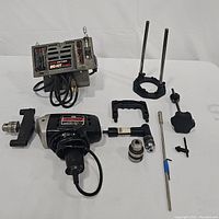 Photo shows all power tools and accessories including drill, router attachment, chucks, rods, and handles laid out on a white surface.