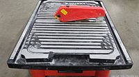 Top view of tile saw platform showing metal surface with grooves and red blade cover.
